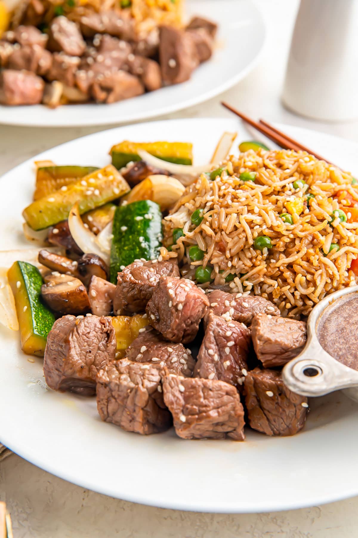A plate of hibachi steak in sauce with stir-fry vegetables and a mound of delicious fried rice.