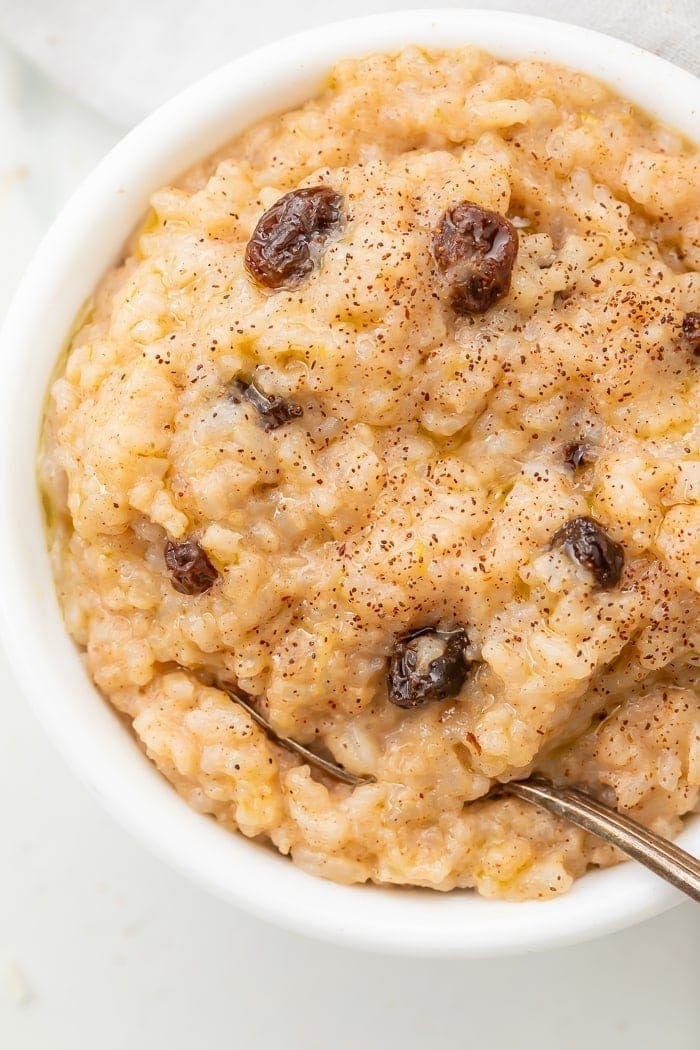 Overhead shot of rice pudding with raisins, sprinkled with cinnamon, with a spoon