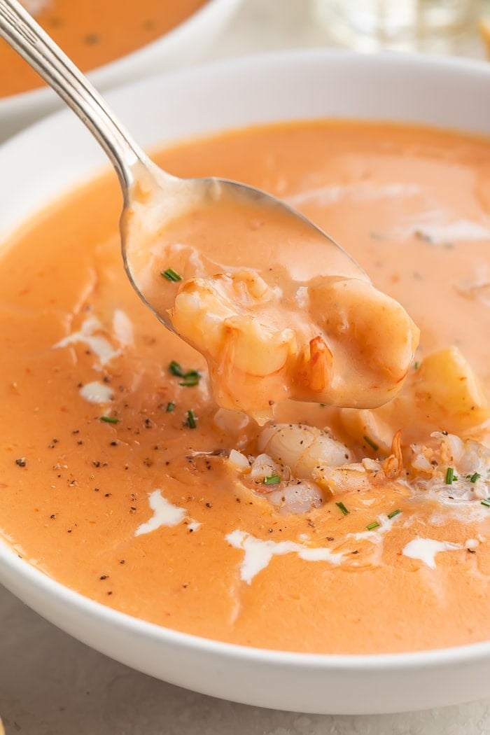 A spoonful of a shrimp bisque being lifted out of a bowl