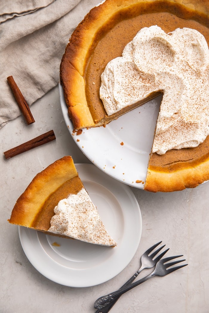 Overhead shot of keto pumpkin pie on a white plate and a pie in a pie dish with a slice missing