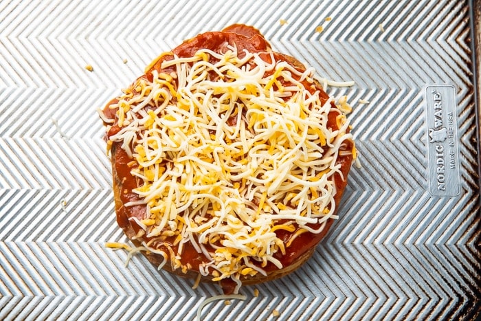 Shredded cheese on top of a Mexican pizza that has not been cooked yet