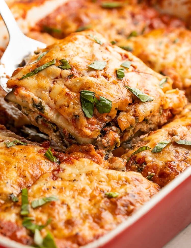 A square of eggplant lasagna being lifted out of a casserole dish of lasagna.