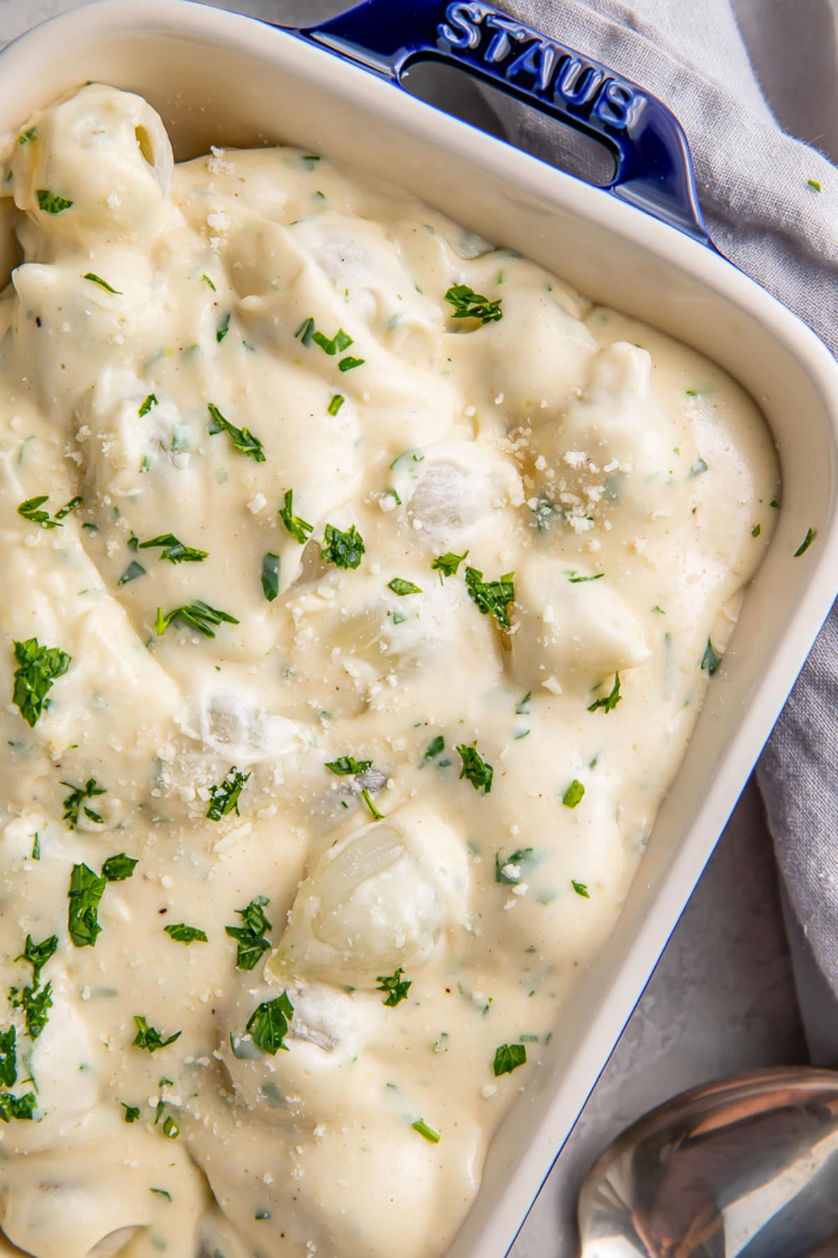 Creamed onions garnished with fresh herbs in a casserole dish.