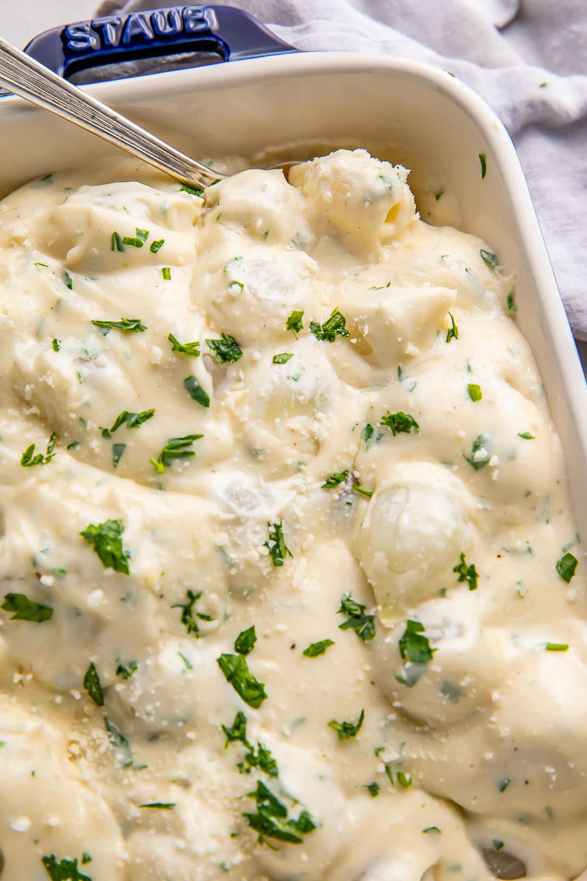 Creamed onions garnished with fresh herbs in a casserole dish.