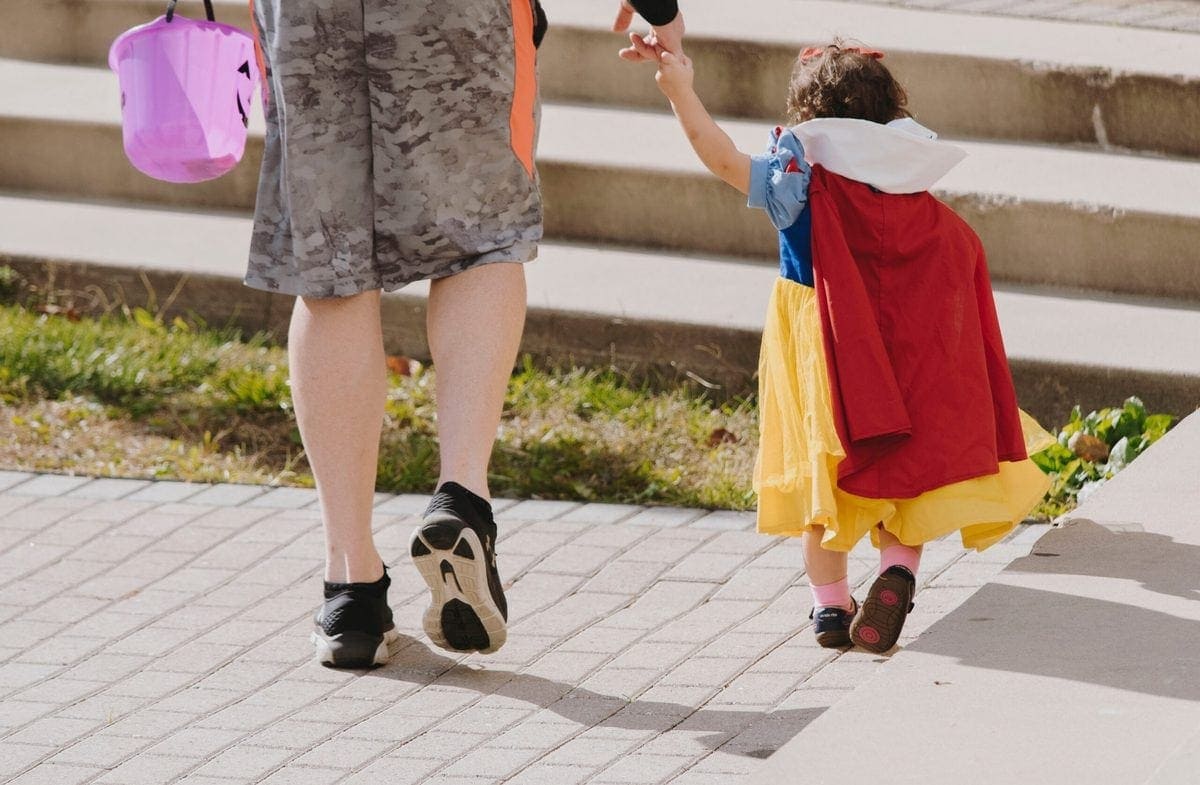 Woman trick-or-treating with little girl dressed as Snow White