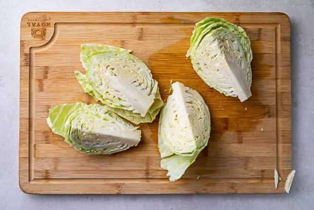 Four wedges of a head of cabbage on a wooden cutting board