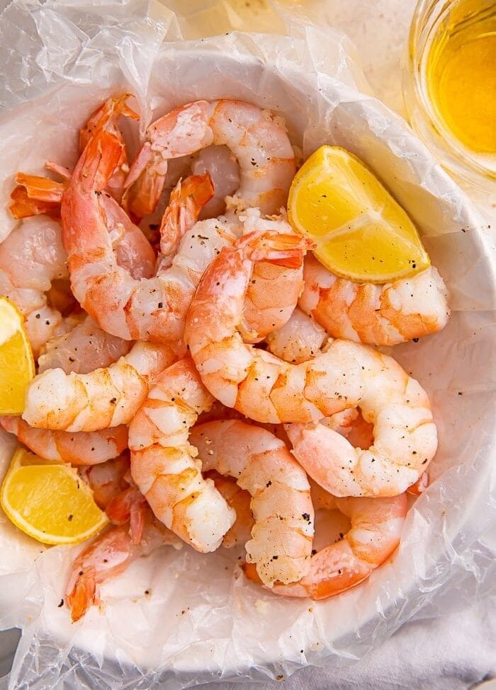 Instant Pot shrimp and lemon wedges inside a bowl lined with parchment paper