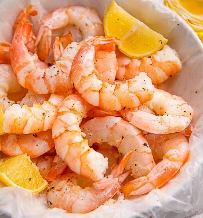 Instant Pot shrimp in a white bowl with lemon wedges