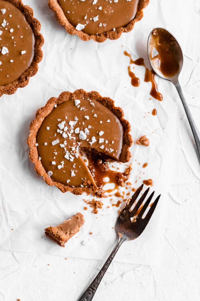 Salted caramel tart with missing piece and crumbs on a marble countertop