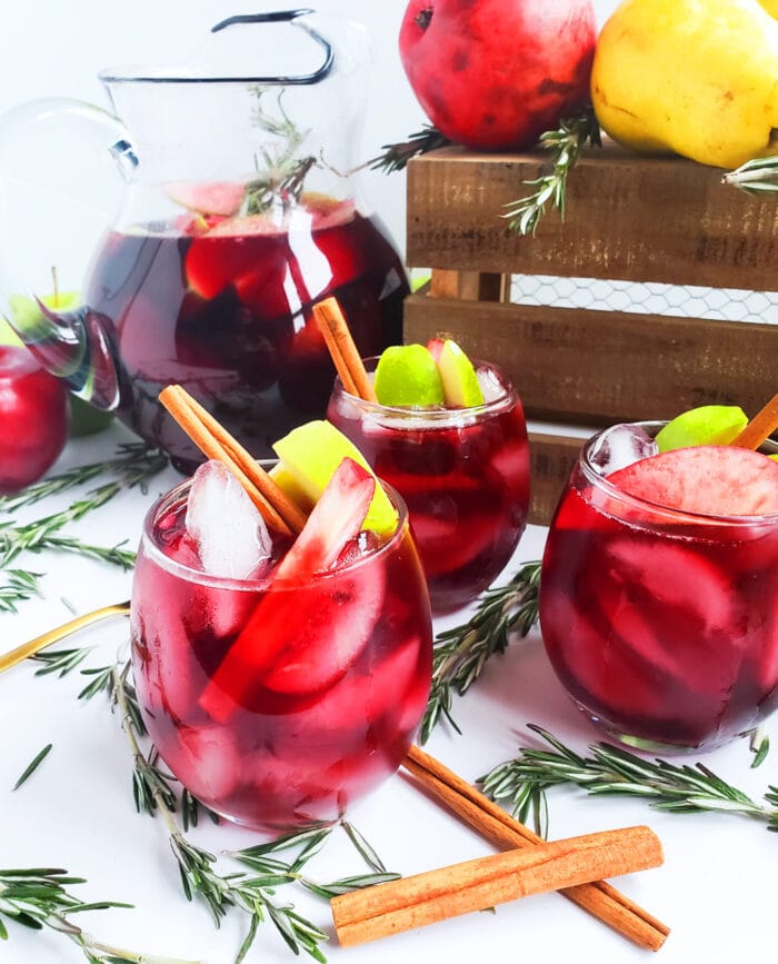 Red harvest sangria in stemless glasses with apples and cinnamon sticks