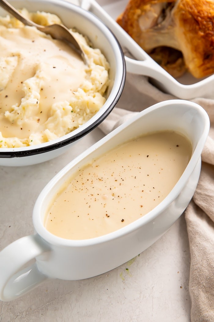 Gravy boat filled with chicken gravy next to a bowl of mashed potatoes