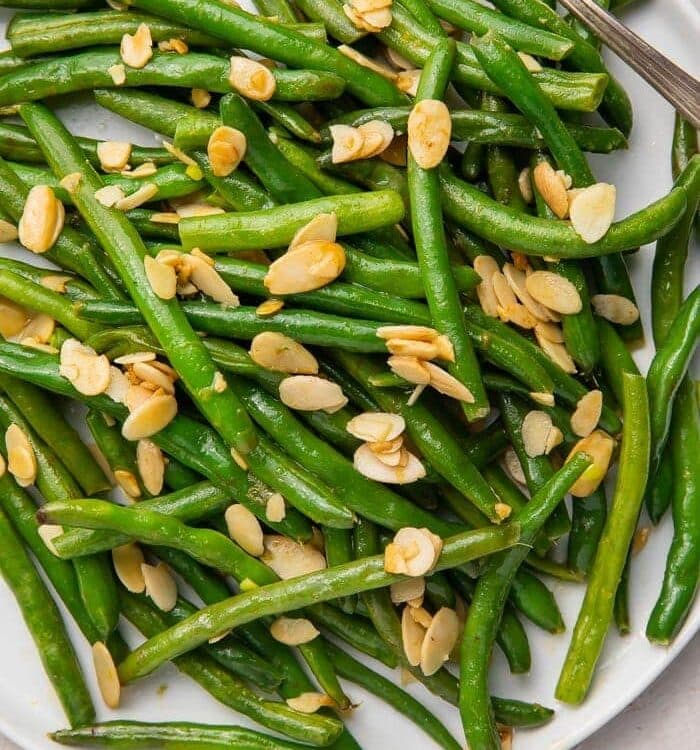 Green beans with almonds on a white platter