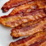 Oven-cooked bacon strips on a white plate