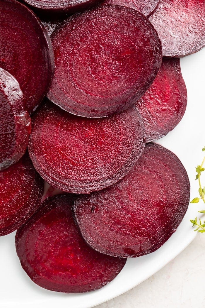 Dark red beets cut into medallions displayed on a white dish