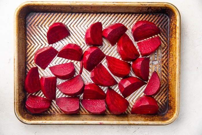 Dark reed beets cut into wedges and placed on silver sheet pan