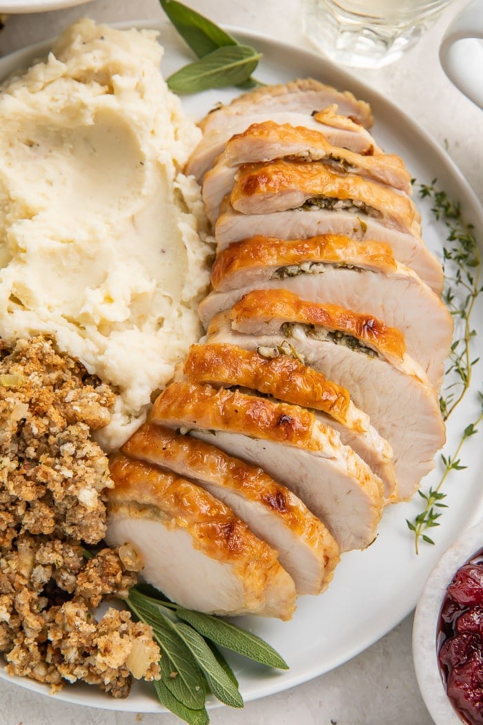 Instant Pot turkey breast slices covered on a plate with mashed potatoes and stuffing