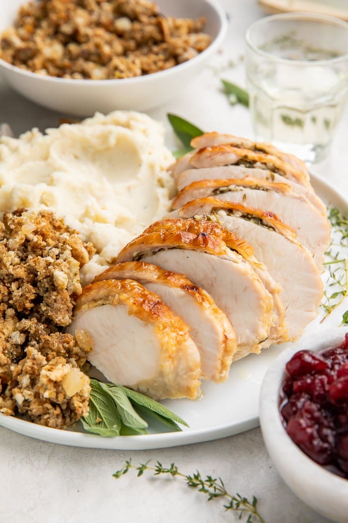 Instant Pot turkey breast slices on a plate with dressing and mashed potatoes