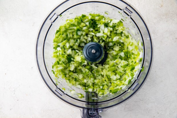 Celery, onion, green bell pepper, garlic chopped in a food processor bowl.