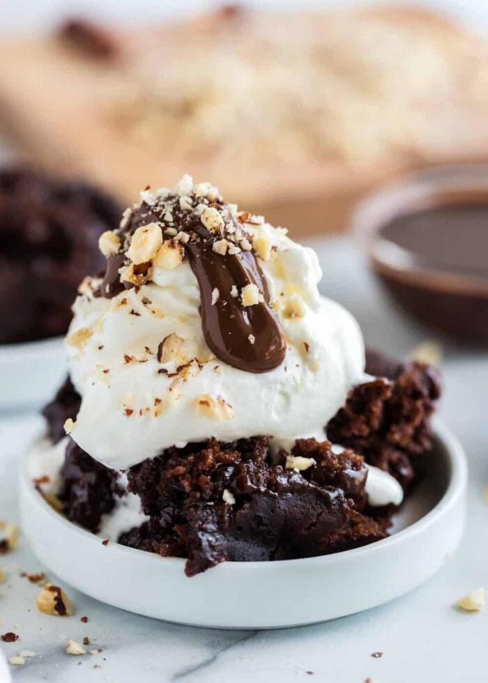 A white bowl of vegetarian slow cooker chocolate cake with vanilla ice cream