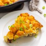 Wedge slice of tater tot breakfast casserole with sausage, egg, and cheese