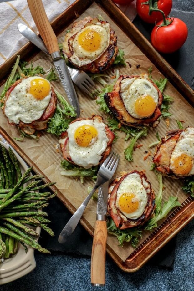 A sheet pan with croque madame, garnish, and silverware