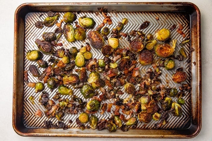 Oven roasted brussels sprouts with bacon on a silver sheet pan