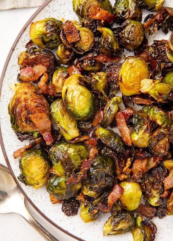 Dark trimmed white plate full of roasted brussels sprouts and bacon