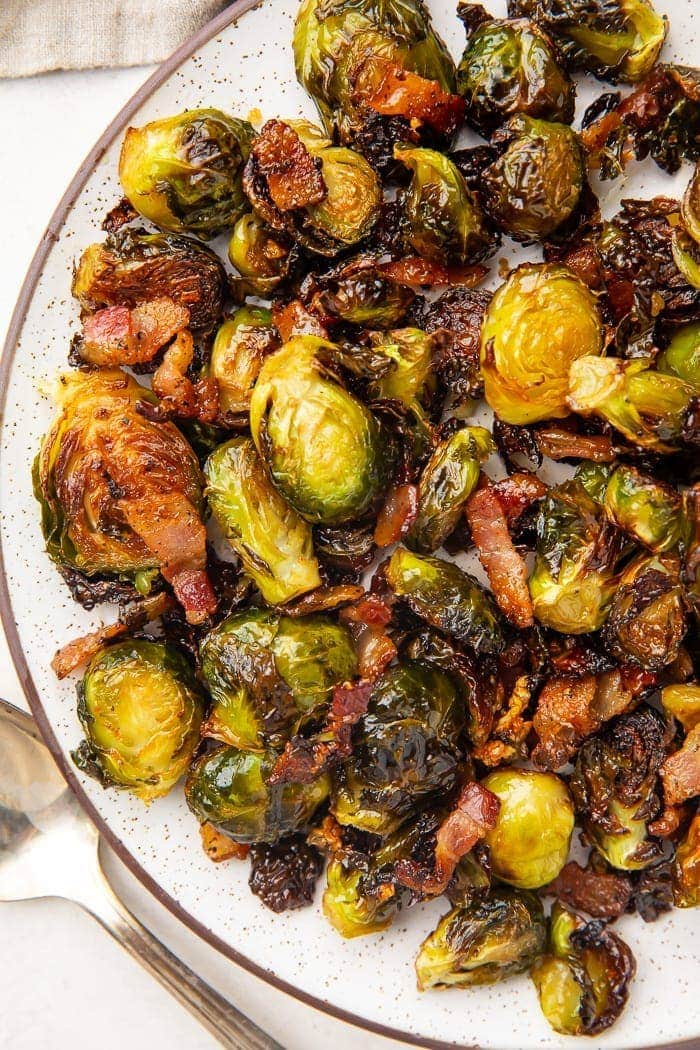 Dark trimmed white plate full of roasted brussels sprouts and bacon