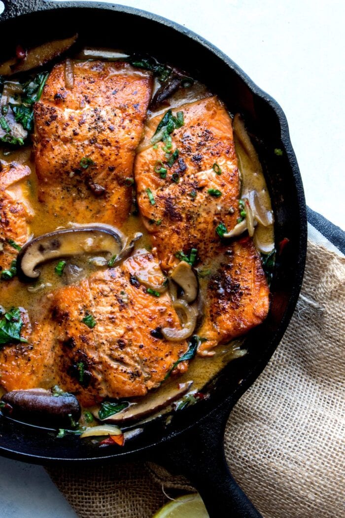 Cast iron skillet with braised salmon in a creamy mushroom sauce
