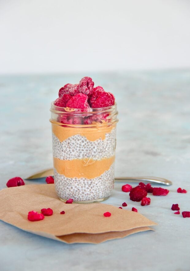 Peanut butter and jelly chia seed pudding in a glass jar topped with rapsberries