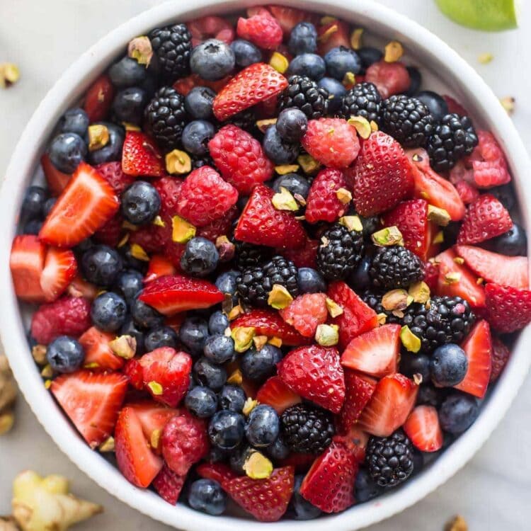 White bowl of mixed berries, ginger, lime, and mint