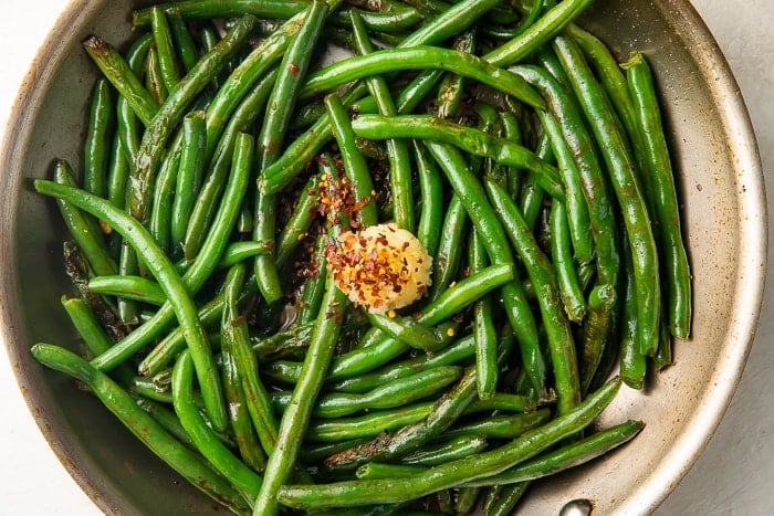 Green beans in skillet with garlic and red pepper flakes
