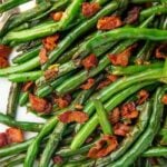Close up of green beans with bacon on a white plate