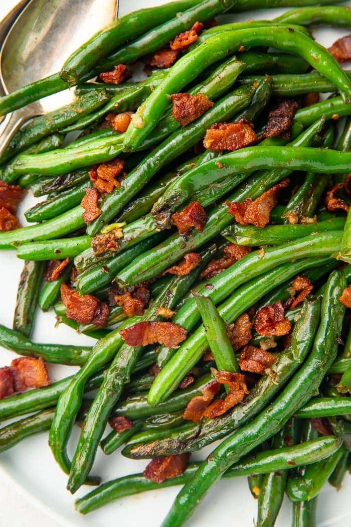 Close up of green beans with bacon on a white plate