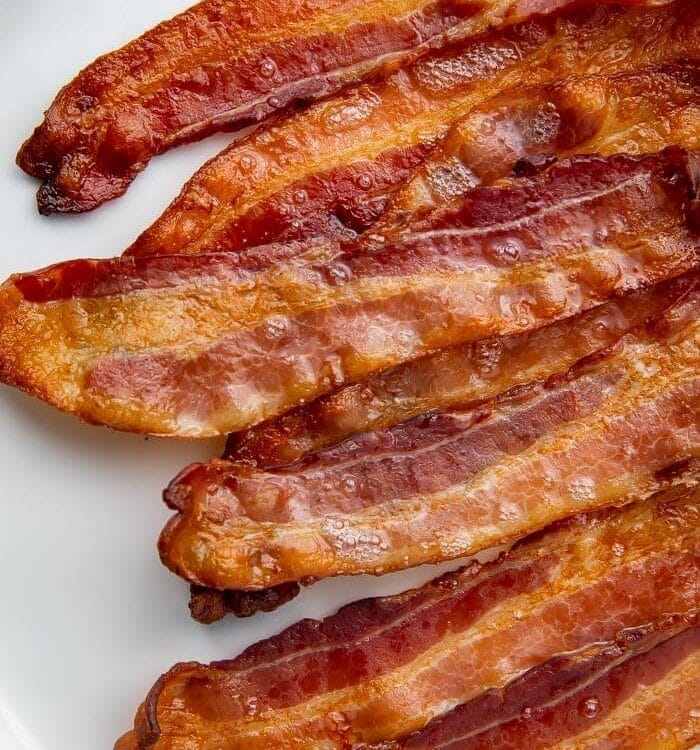 White serving plate with slices of crispy bacon