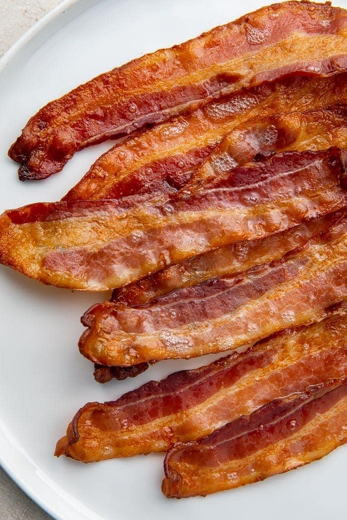 White serving plate with slices of crispy bacon