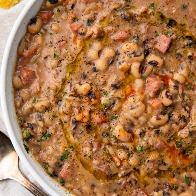 White bowl holding instant pot black eyed peas with ham, bacon, and onion