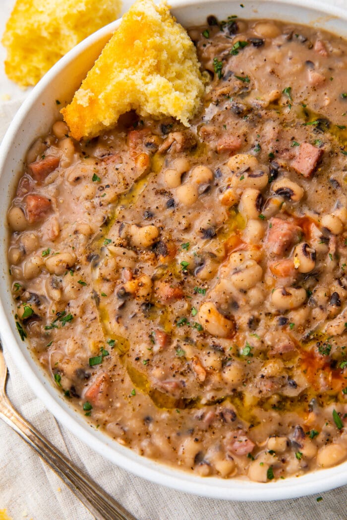 Instant pot black eyed peas served with a piece of cornbread in a white bowl