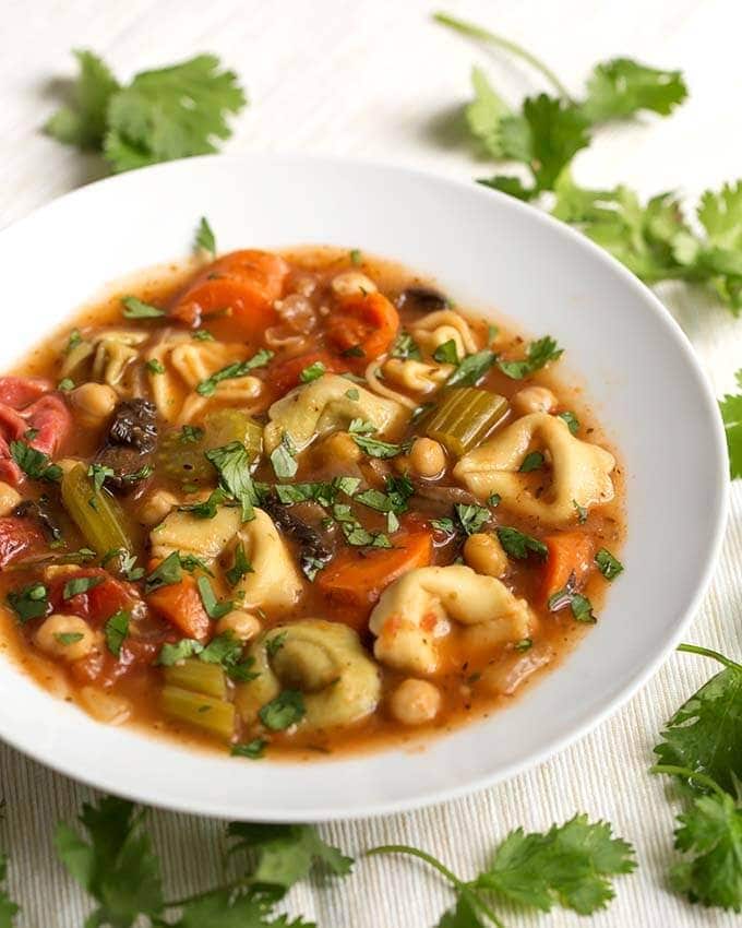 Vegetable tortellini Instant Pot soup in a white bowl with green parsley garnish