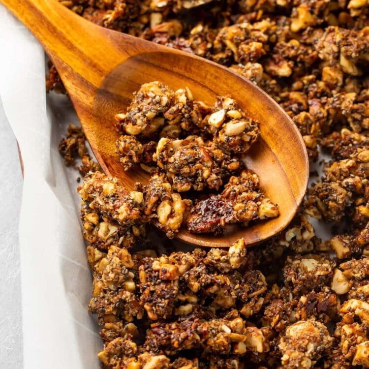 Baked keto granola on a sheet pan with a wooden spoon