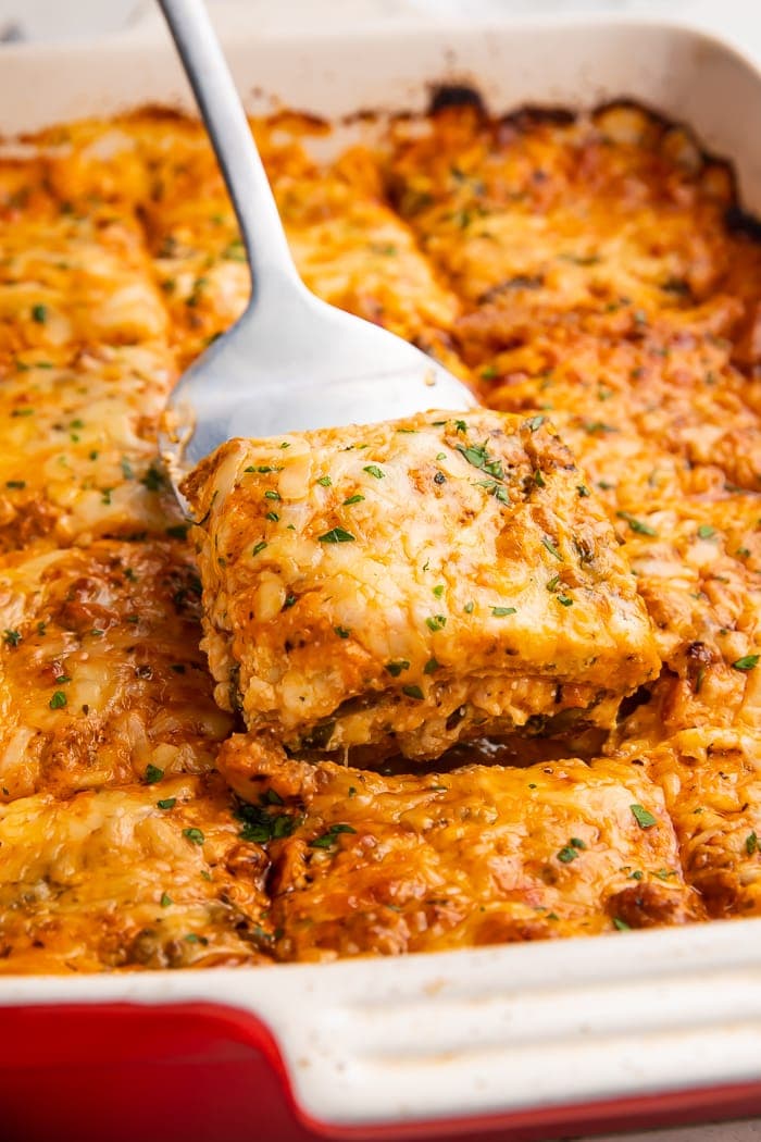 Slice of keto lasagna being lifted out of a casserole dish with a spatula