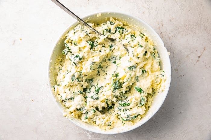 Spinach and ricotta mixture in a white mixing bowl