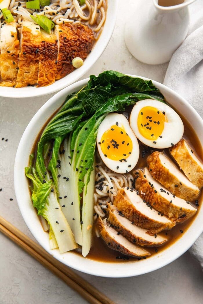 A white bowl of keto ramen with shirataki noodles, ramen eggs, chicken, and bok choy