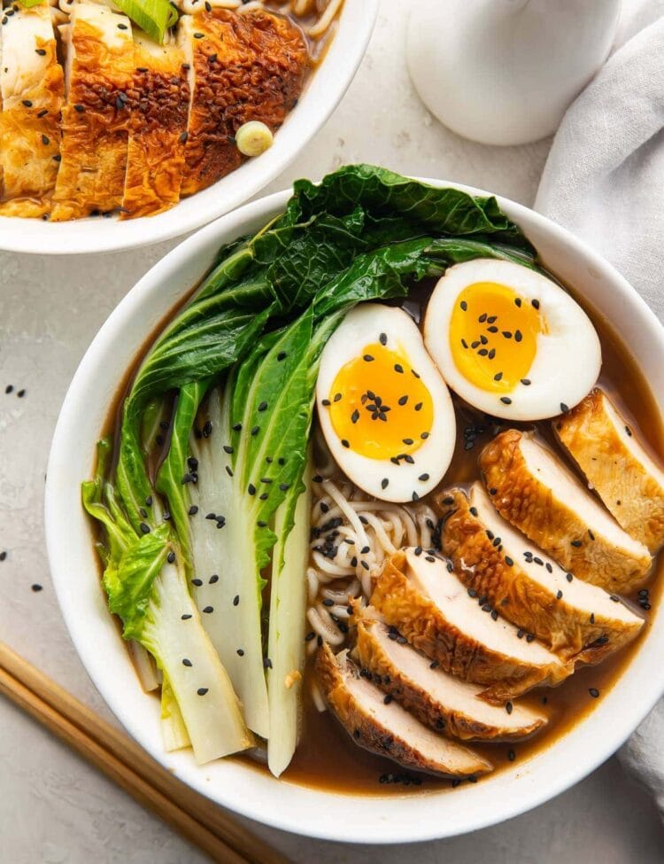 A white bowl of keto ramen with shirataki noodles, ramen eggs, chicken, and bok choy