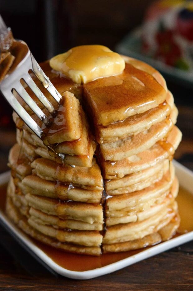 A stack of keto pancakes covered in maple syrup topped with butter