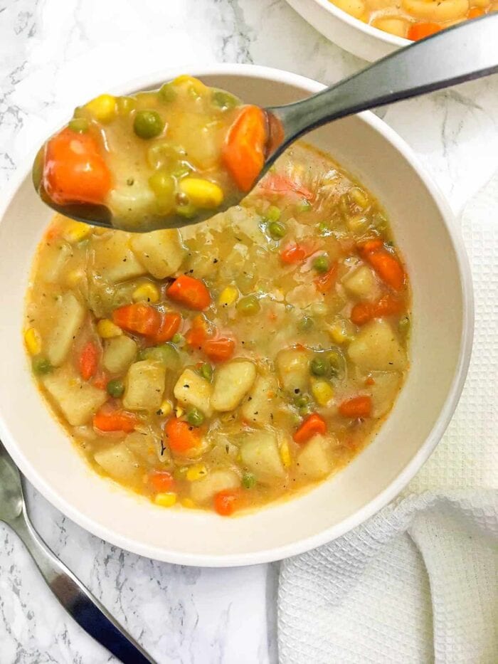 Vegetarian slow cooker pot pie stew in a white bowl with a spoon