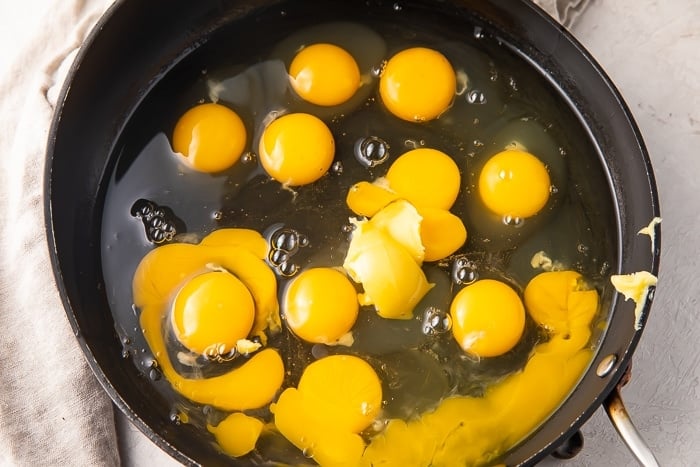 A dozen cracked eggs and ghee in a deep saucepan