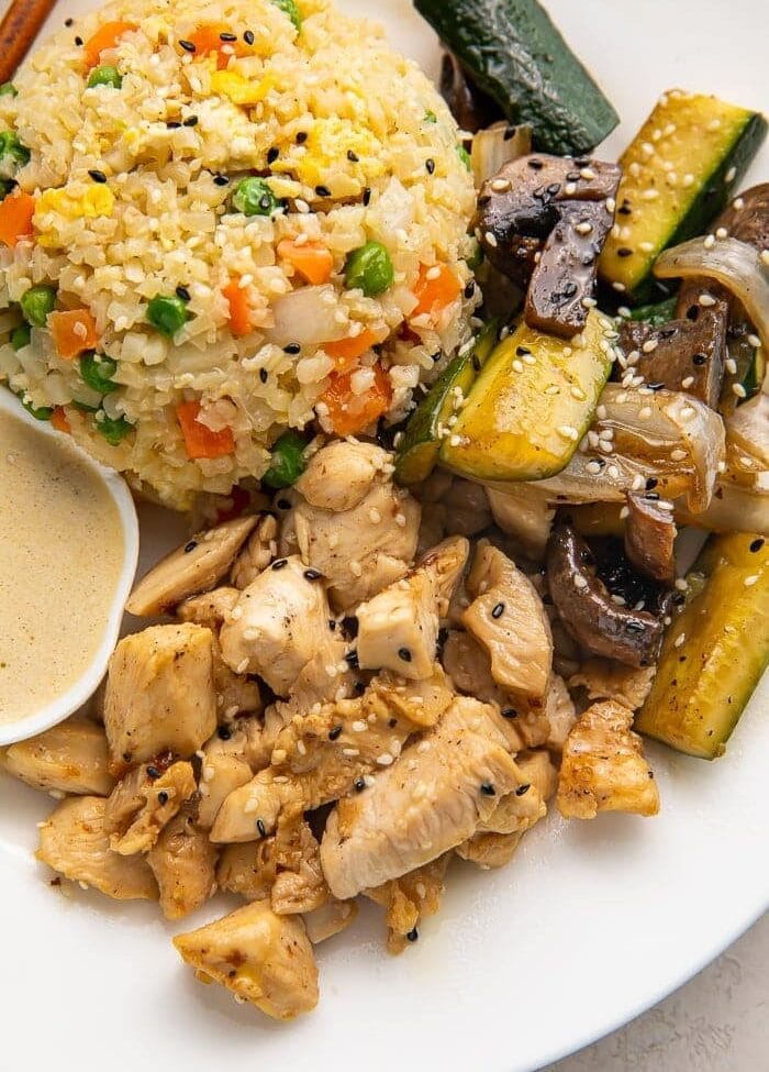 Close up photo of whole30 hibachi chicken, rice, and veggies on a white plate