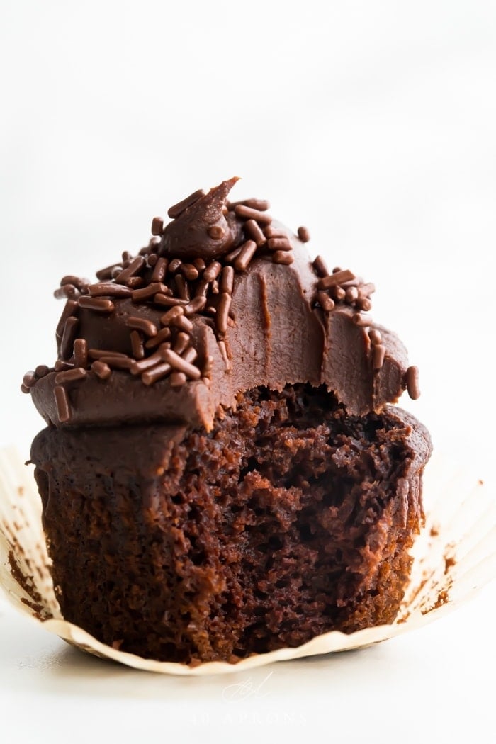 Paleo chocolate cupcakes topped with chocolate frosting, with one bite missing