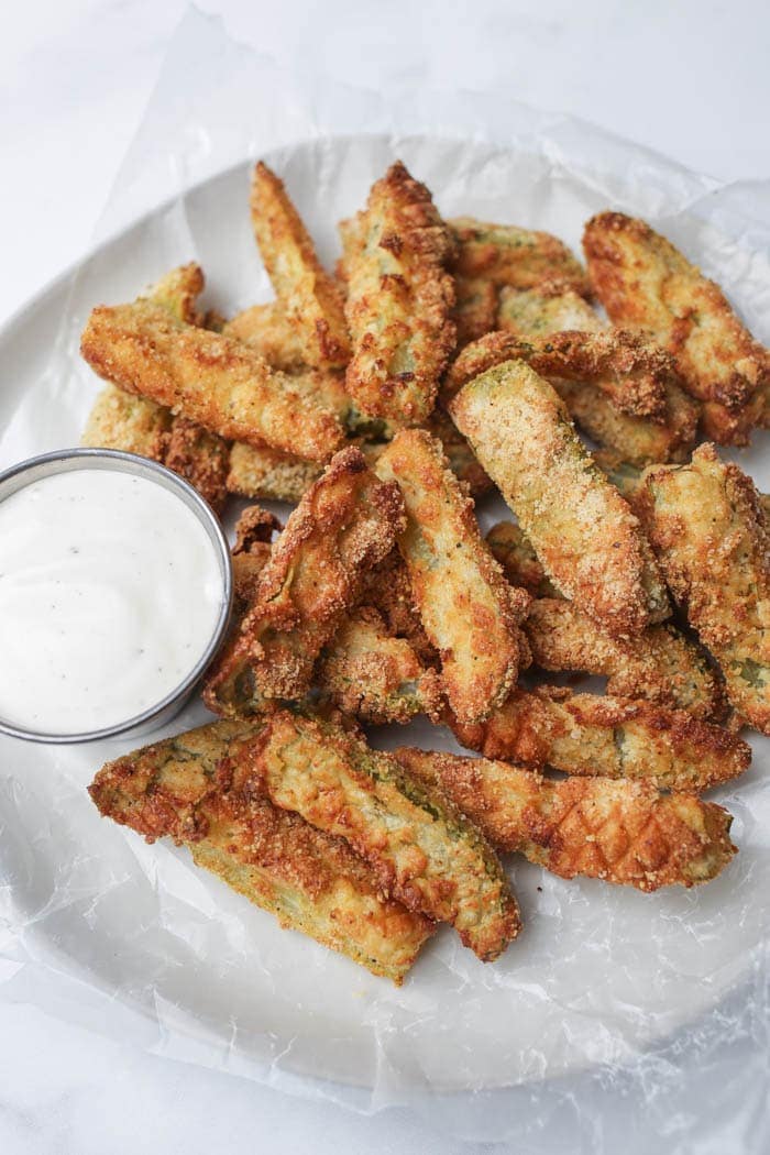 Air fried pickles on a white plate with a side of ranch